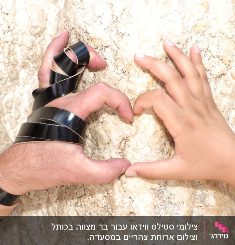 ידיים יוצרות צורת לב על רקע אבן